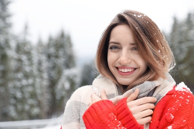 Young woman in warm clothes outdoors on snowy day. Winter vacation