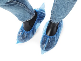 Photo of Woman wearing blue shoe covers onto her boots against white background, top view