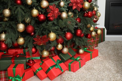 Many gift boxes under decorated Christmas tree in room