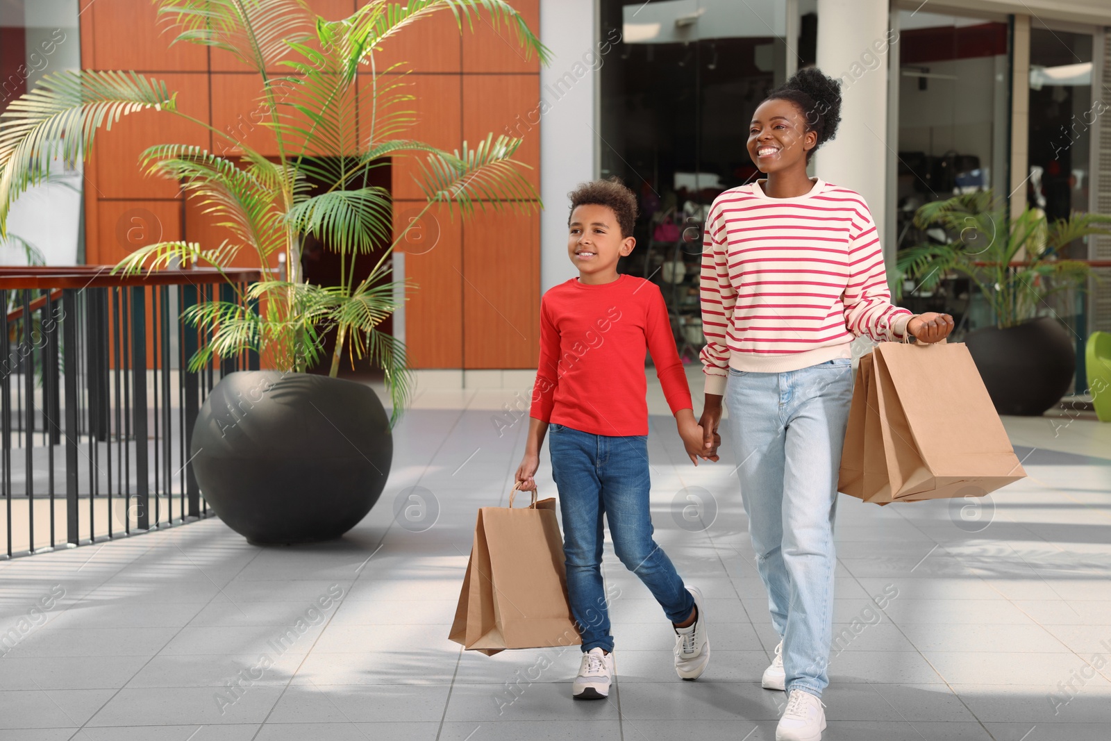 Photo of Family shopping. Happy mother and son with purchases in mall