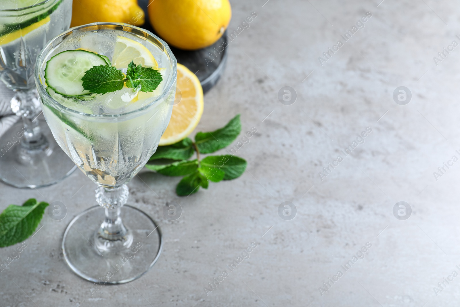 Photo of Refreshing water with cucumber, lemon and mint on grey table. Space for text