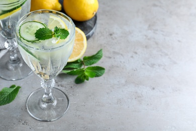 Refreshing water with cucumber, lemon and mint on grey table. Space for text
