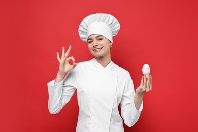 Photo of Professional chef holding egg and showing OK gesture on red background