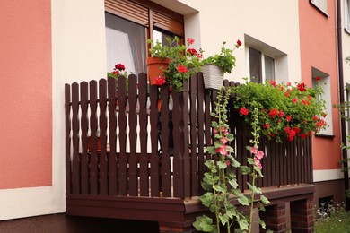 Photo of Wooden balcony decorated with beautiful red flowers