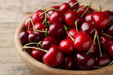 Photo of Fresh ripe cherries in wooden bowl on table, closeup