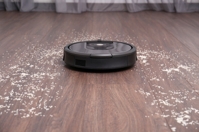 Removing groats from wooden floor with robotic vacuum cleaner at home