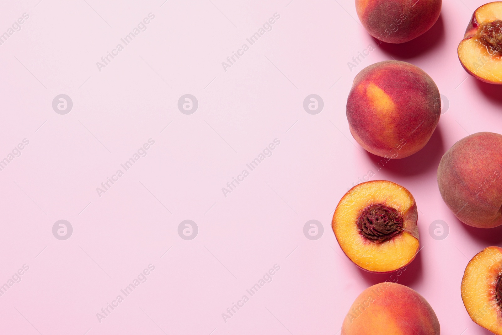 Photo of Cut and whole fresh ripe peaches on pink background, flat lay. Space for text