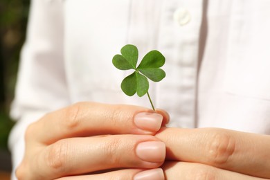 Photo of Woman holding green clover leaf, closeup view