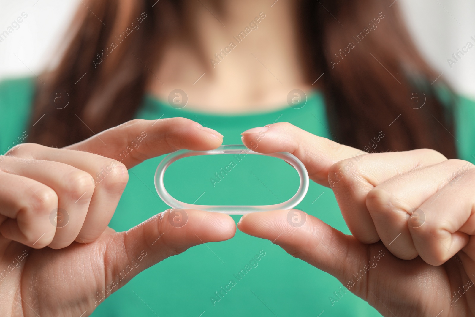 Photo of Woman holding diaphragm vaginal contraceptive ring on blurred background, closeup