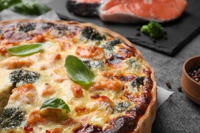 Photo of Delicious homemade quiche with salmon and broccoli on gray table, closeup