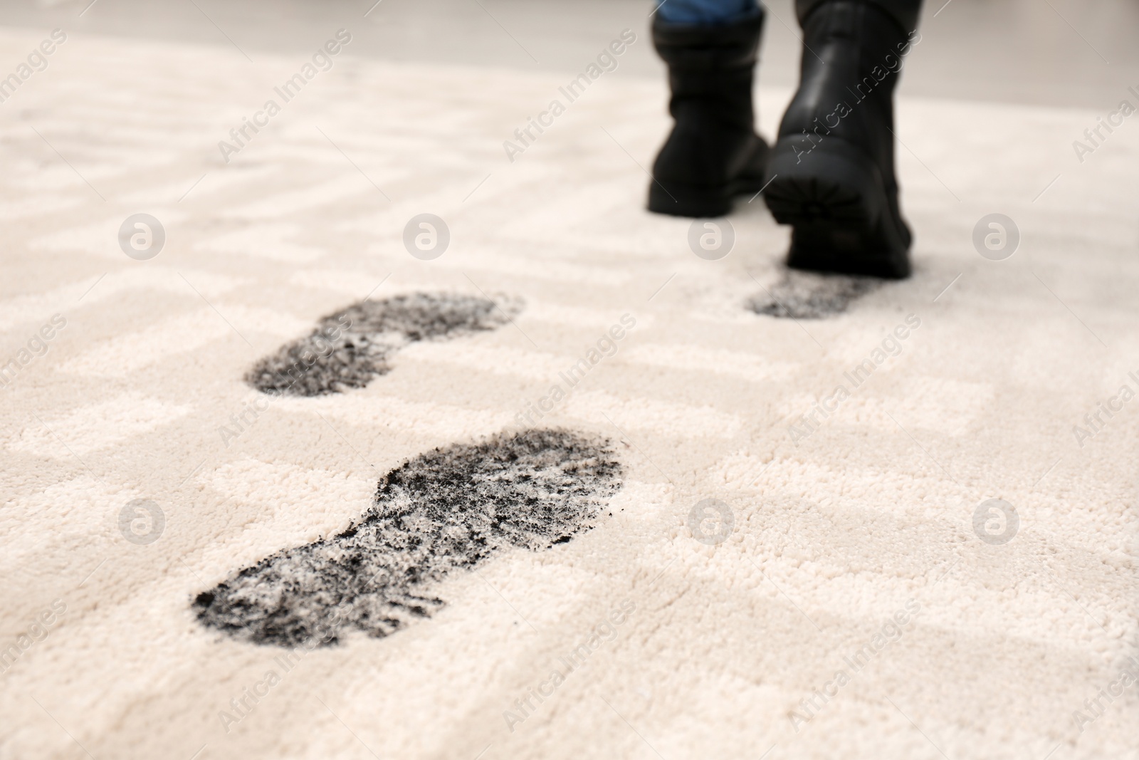 Photo of Person in dirty shoes leaving muddy footprints on carpet