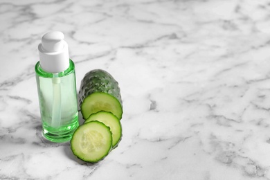 Photo of Fresh cut cucumber and tonic in bottle on table. Space for text