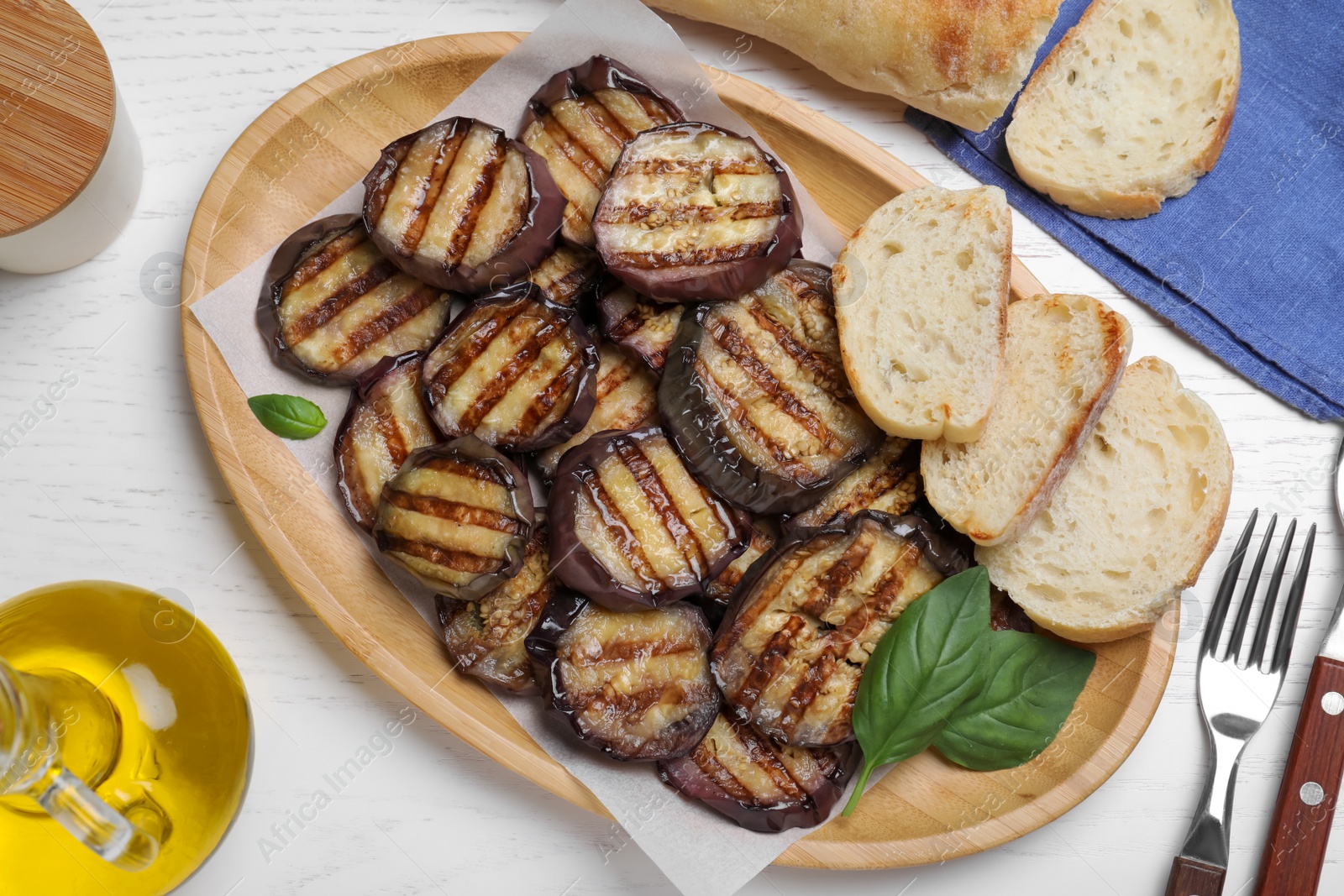 Photo of Delicious grilled eggplant slices served on white wooden table, flat lay