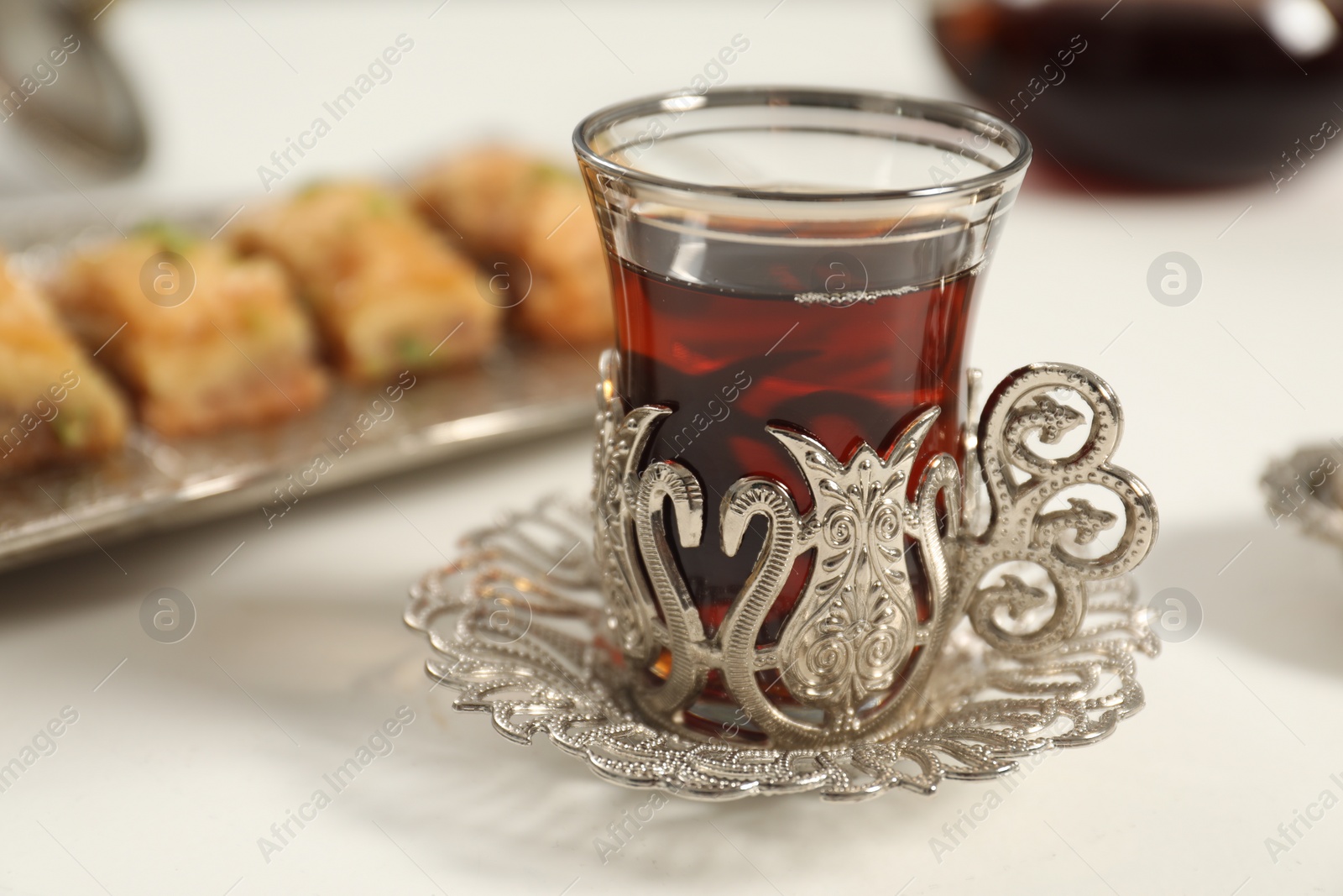 Photo of Cup of delicious Turkish tea served on white table, closeup