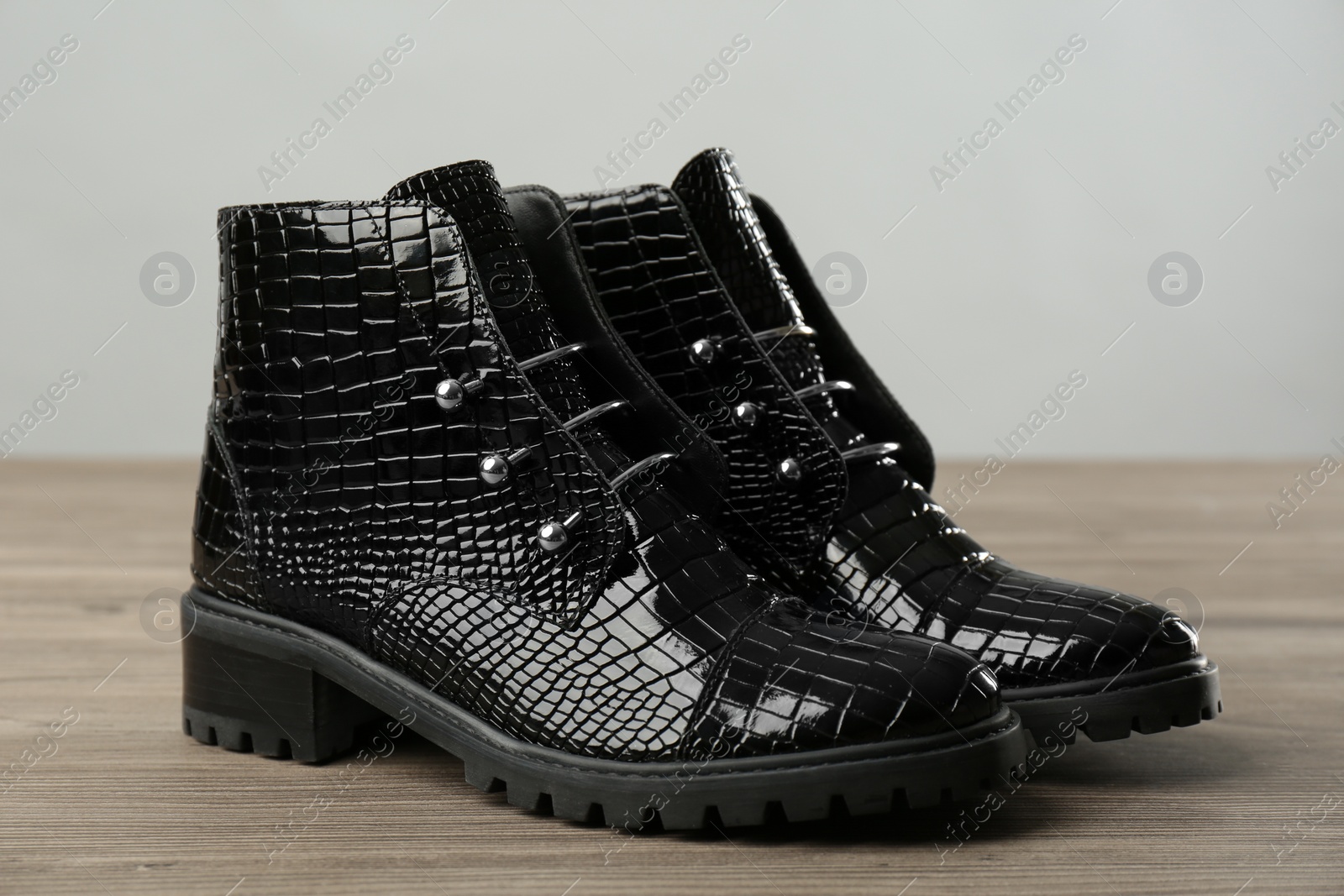 Photo of Pair of stylish ankle boots on wooden background, closeup