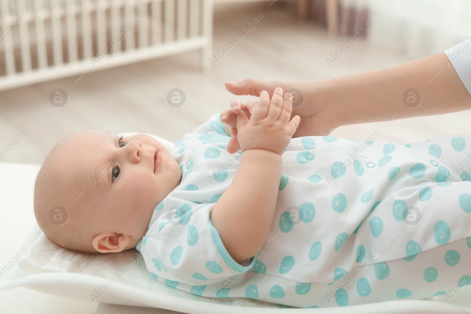 Photo of Doctor weighting baby on scales in light room