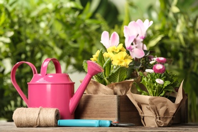 Photo of Blooming flowers and gardening equipment on table outdoors