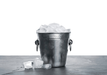 Metal bucket with ice cubes on table against white background