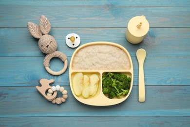 Photo of Toys, pacifier and plastic dishware with healthy baby food on light blue wooden table, flat lay