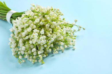 Beautiful lily of the valley bouquet on light blue background, closeup. Space for text