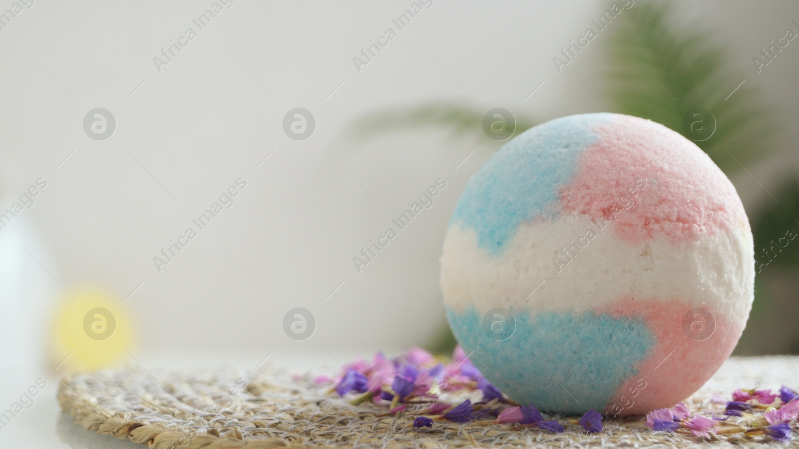 Photo of Beautiful bath bomb on wicker mat indoors, space for text