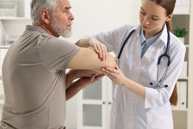 Photo of Arthritis symptoms. Doctor examining patient's elbow in hospital