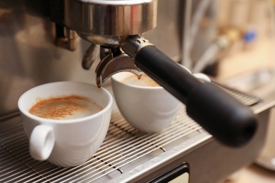 Photo of Coffee machine with cups on drip tray, closeup