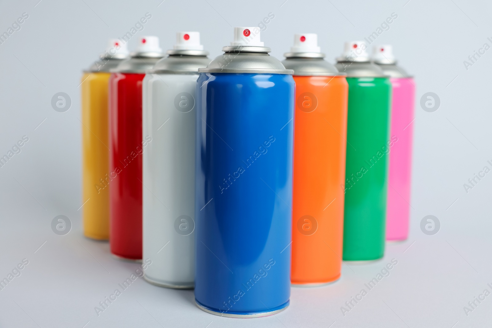 Photo of Colorful cans of spray paints on light grey background