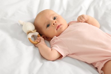 Photo of Cute little baby with toy on white sheets