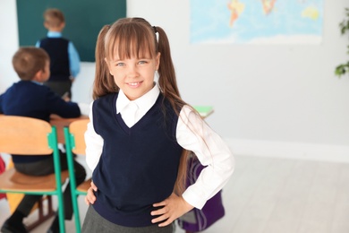 Photo of Little girl in classroom. Stylish school uniform