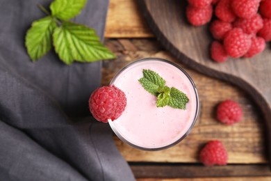 Photo of Glass of tasty fresh raspberry smoothie on wooden table, flat lay
