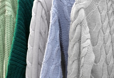 Photo of Collection of warm sweaters as background, closeup