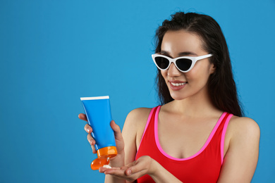 Young woman applying sun protection cream on dark blue background