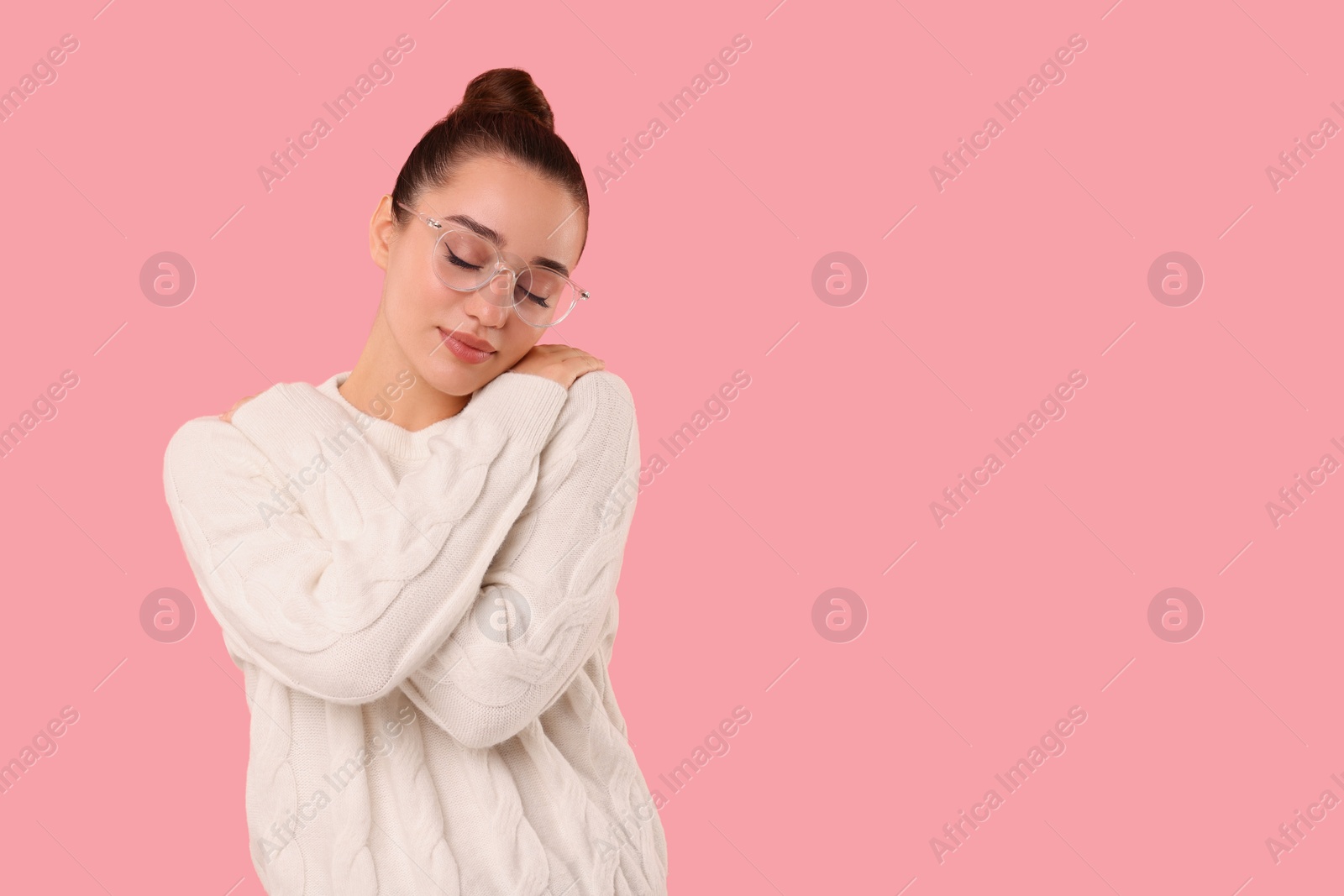 Photo of Beautiful young woman in stylish warm sweater on pink background, space for text