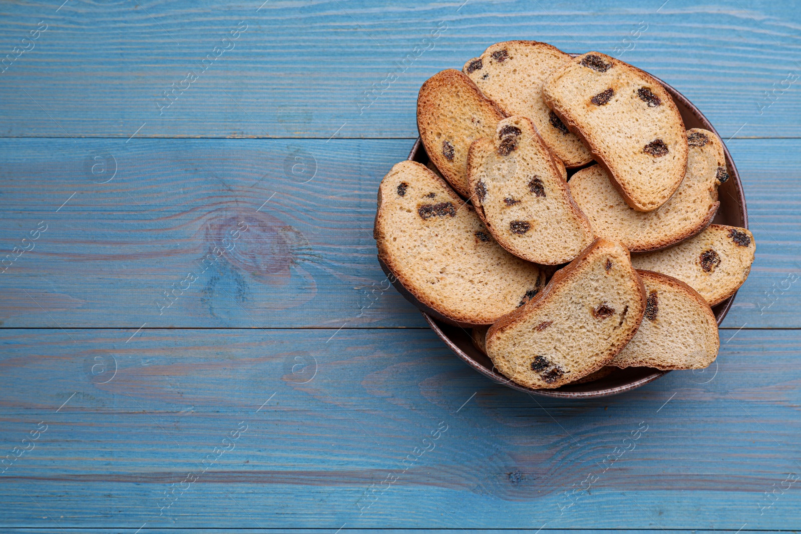 Photo of Sweet hard chuck crackers with raisins on light blue wooden table, top view. Space for text