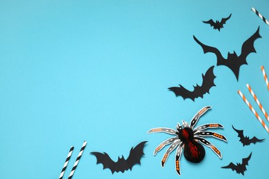 Photo of Flat lay composition with paper bats, spider and cocktail straws on light blue background, space for text. Halloween decor