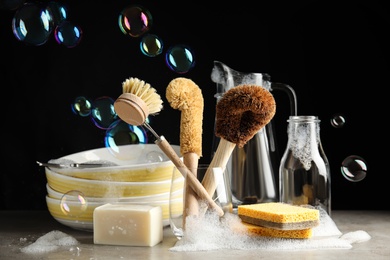 Photo of Cleaning supplies for dish washing and soap bubbles on black background