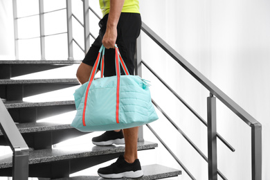 Photo of Man with sports bag on stairs indoors, closeup