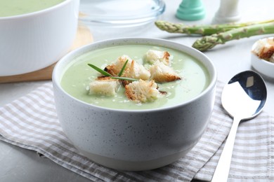 Photo of Bowl of delicious asparagus soup on light grey table