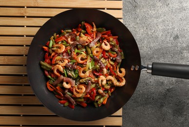 Photo of Shrimp stir fry with vegetables in wok on grey table, top view