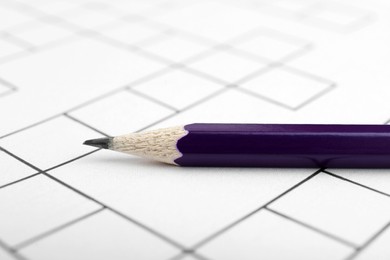Photo of Pencil on blank crossword, closeup view. Intellectual entertainment