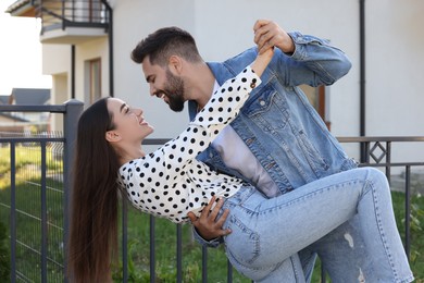 Happy couple dancing near house on city street