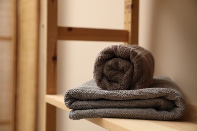 Photo of Soft towels on wooden shelf indoors, closeup