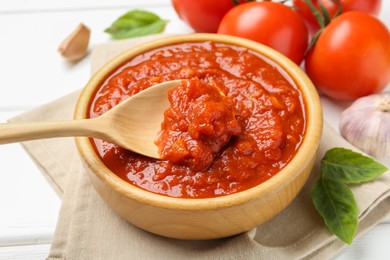 Photo of Homemade tomato sauce and spoon in bowl on white table, closeup