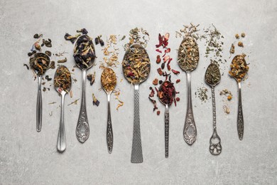 Photo of Flat lay composition with different dry teas and spoons on light table