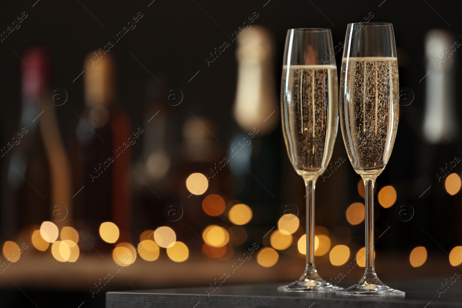 Photo of Glasses of champagne on table against blurred background. Space for text