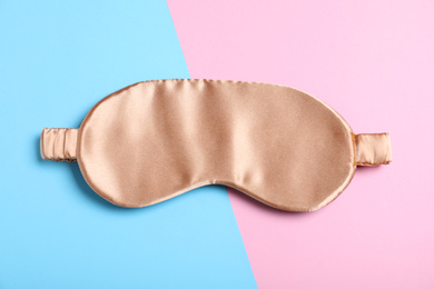 Photo of Beige sleeping mask on color background, top view. Bedtime accessory