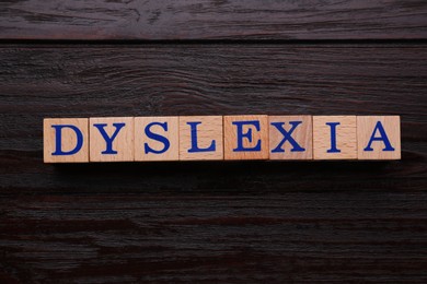 Photo of Cubes with word Dyslexia on wooden background, flat lay