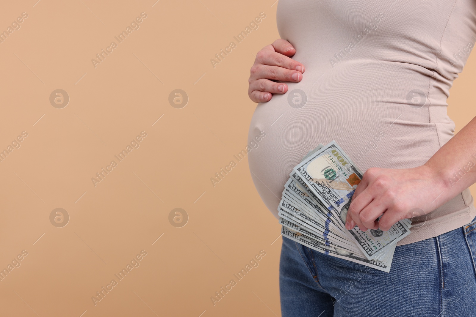 Photo of Surrogate mother. Pregnant woman with dollar banknotes on beige background, closeup. Space for text