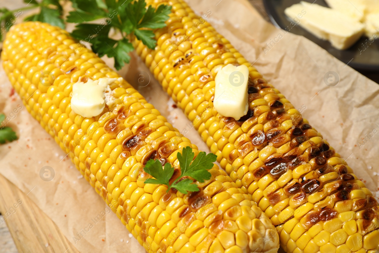 Photo of Tasty grilled corn on parchment, closeup view